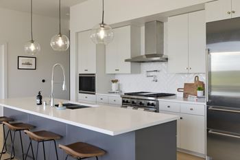 A modern kitchen with a white countertop and stainless steel appliances.